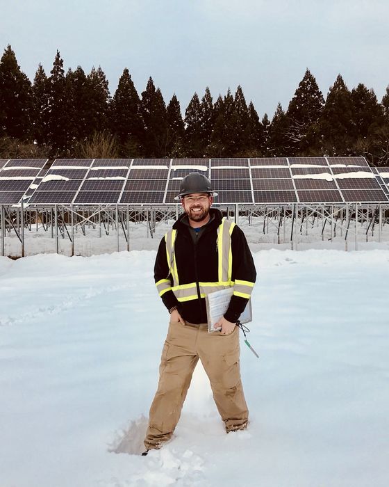 Knee-deep in snow in front of a partly cleared array, holding a tablet.