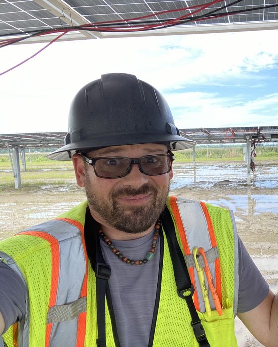 Shrugging beside a flooded tracker field, cables hanging overhead.