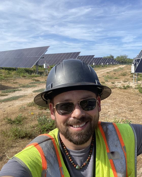 Selfie among dual-axis trackers with yellow flowers in the foreground.