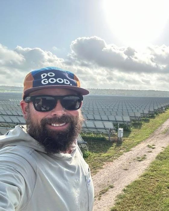Selfie in a DO GOOD cap at the head of a long aisle through a large tracker site.