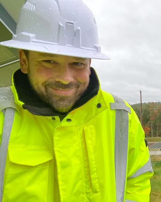 Rain-soaked white hard hat beside a fixed-tilt array in autumn.
