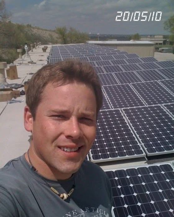 Rooftop selfie beside a monocrystalline array.