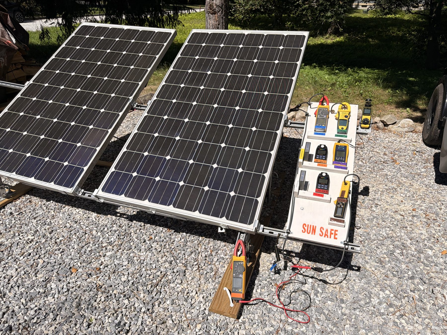 Two PV modules on a test frame beside a board of handheld meters.